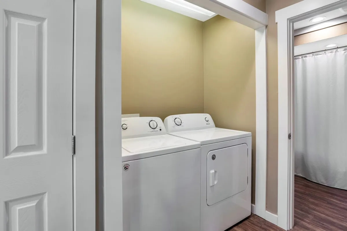 A dedicated laundry area with a washer, dryer, and ample folding space. The setup is clean and organized, suggesting efficiency and attention to comfort for long-term stays.